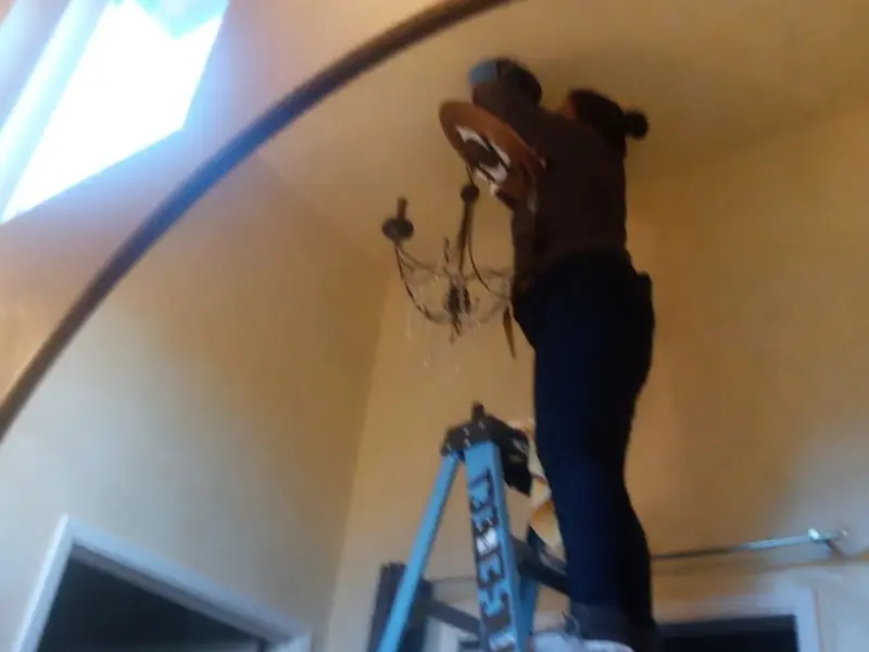 Electrician installing a chandelier in a North Beaver residence